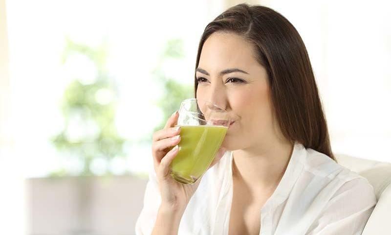 mujer bebiendo zumo verde