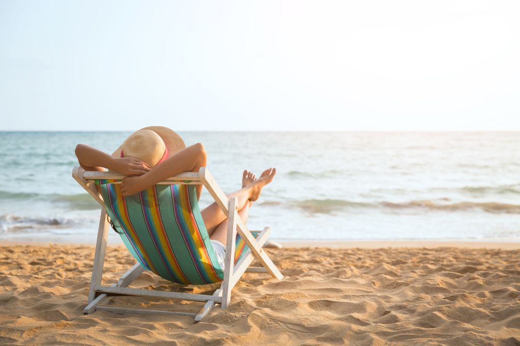 mujer relajada en una hamaca en la playa mirando al mar