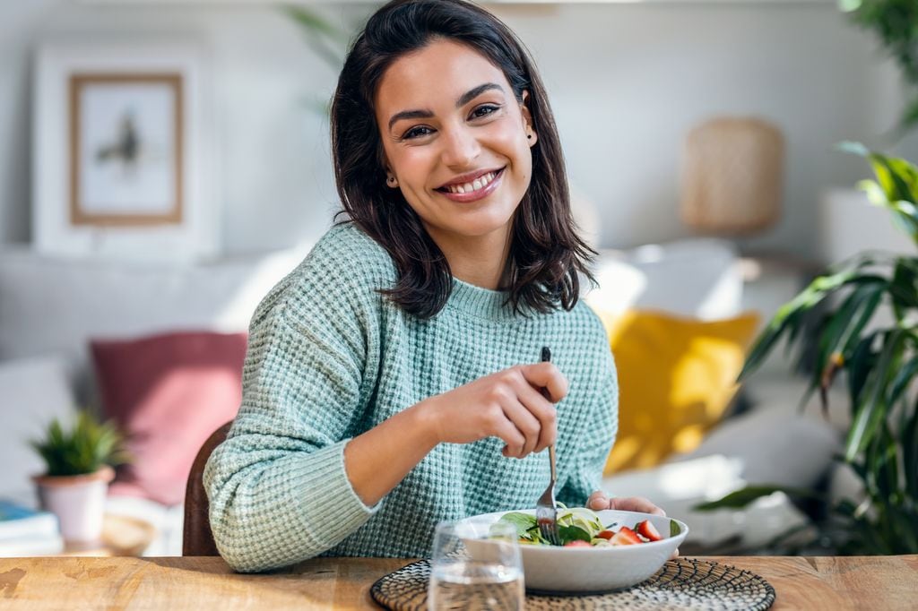 Mujer sonriente tomando una ensalada