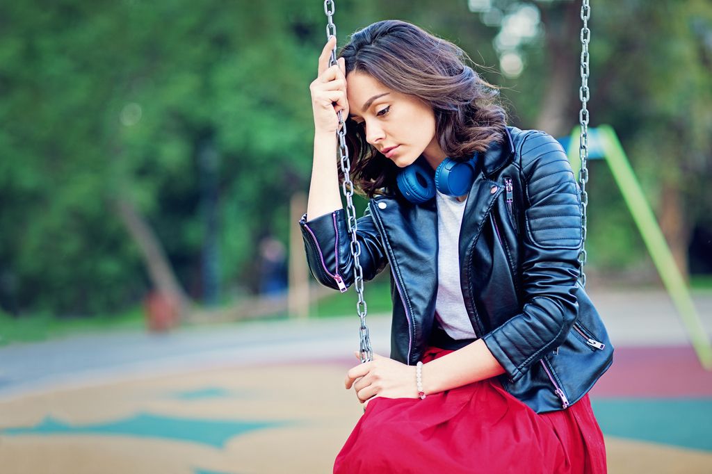 mujer triste sentada en un columpio