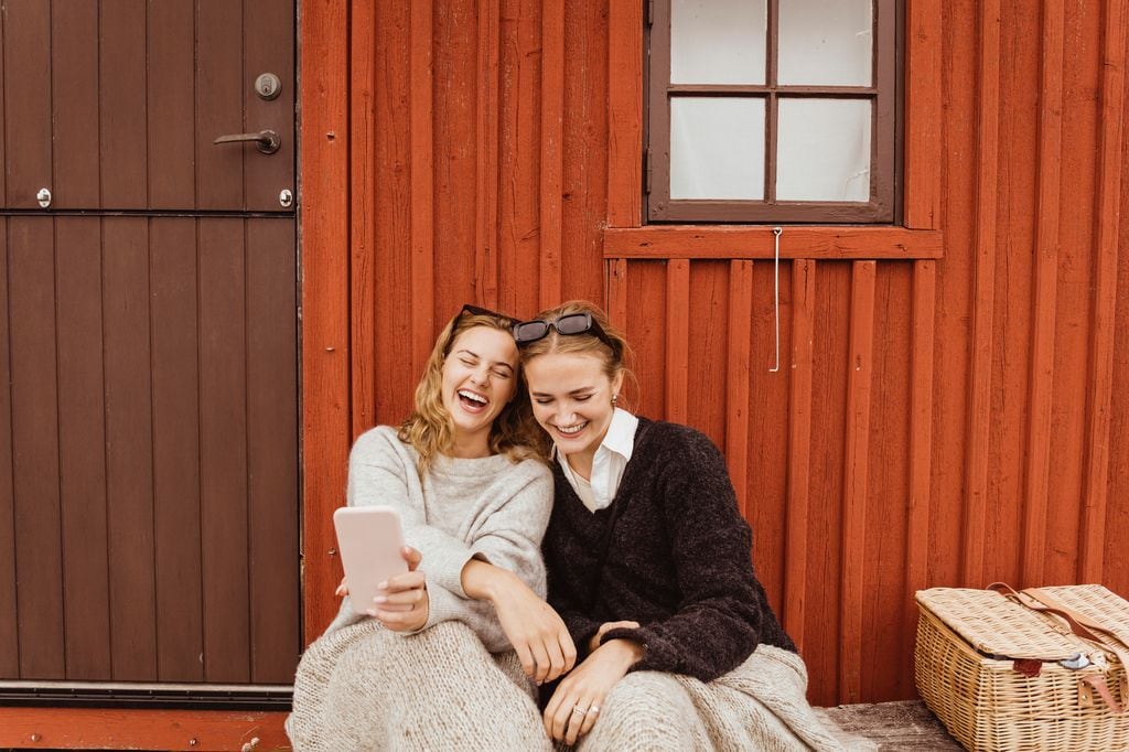 dos amigas riéndose mientras miran el teléfono móvil