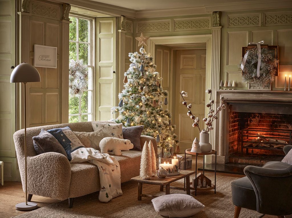 Salón con chimenea, árbol de Navidad blanco, textiles navideños y velas