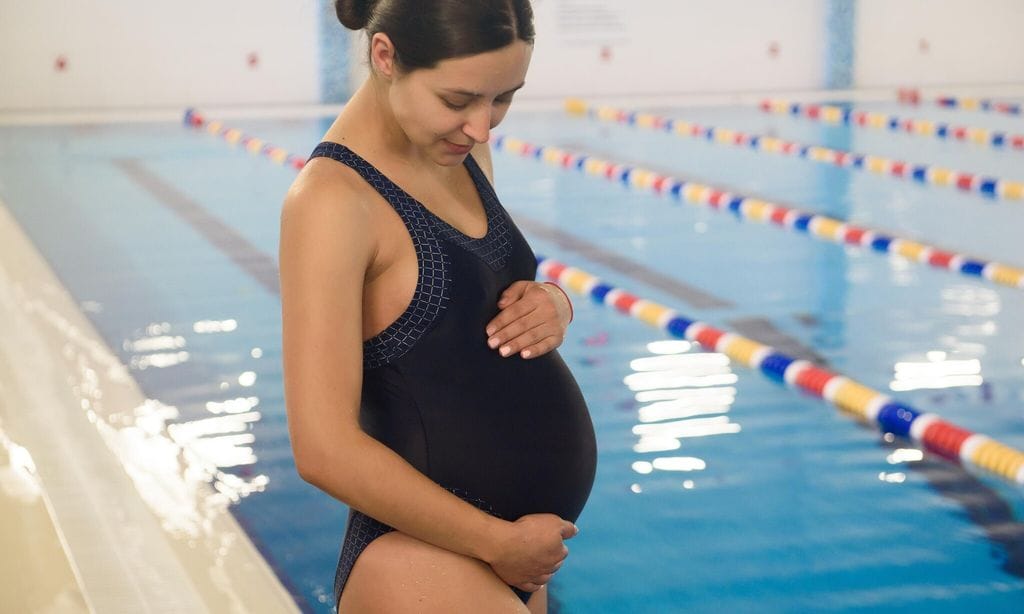 mujer con ba ador en la piscina acarici ndose la barriga