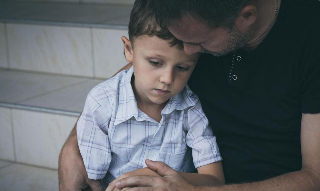 ni o triste en brazos de su padre