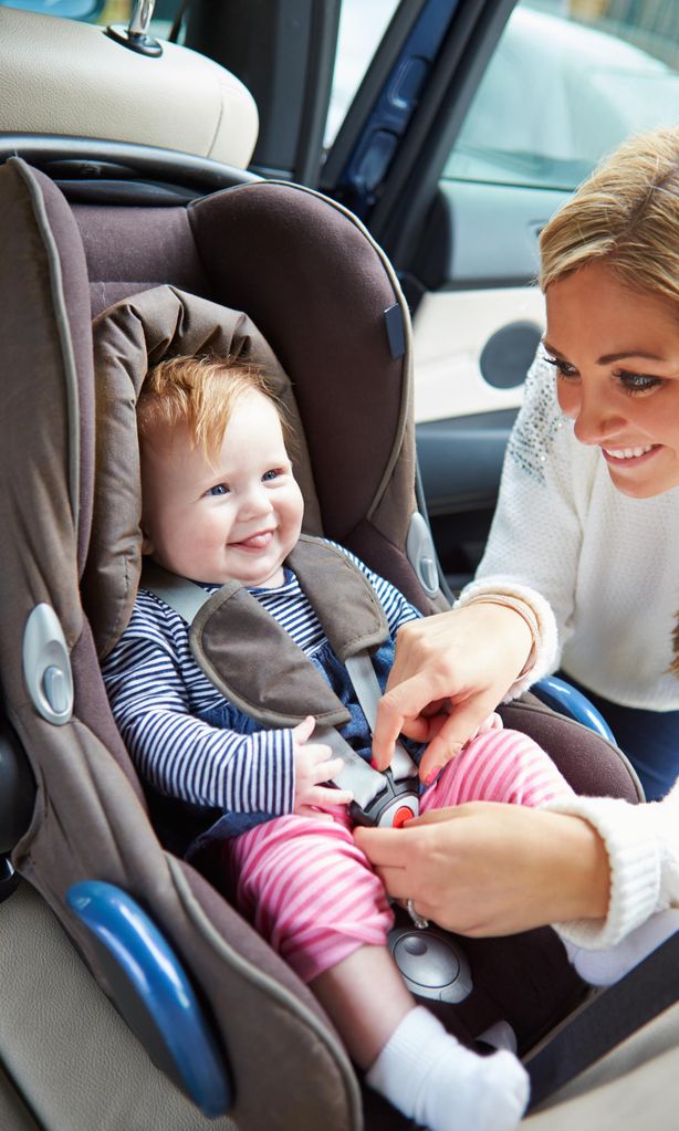 Mamá ajustando cinturón de seguridad sillita bebé en el coche