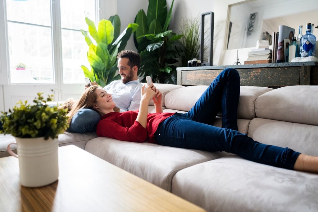 pareja descansando en el sofá, mirando sus móviles