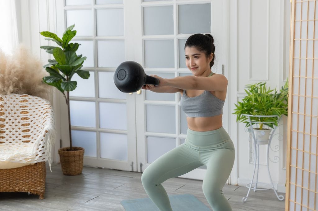 mujer haciendo ejercicio en casa con una kettlebell