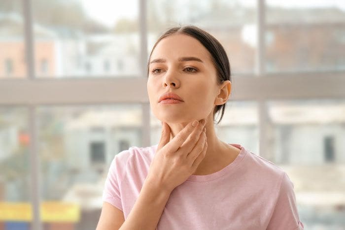 mujer palpándose los ganglios del cuello