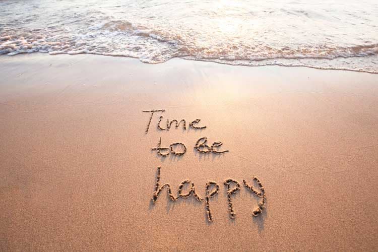Una playa donde aparece escrito sobre la arena 'tiempo de ser feliz'
