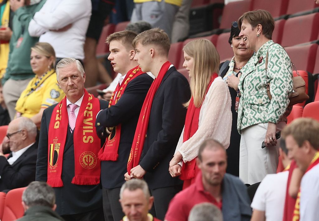 Los miembros de la familia real belga, con la bufanda roja al cuello para animar a los suyos