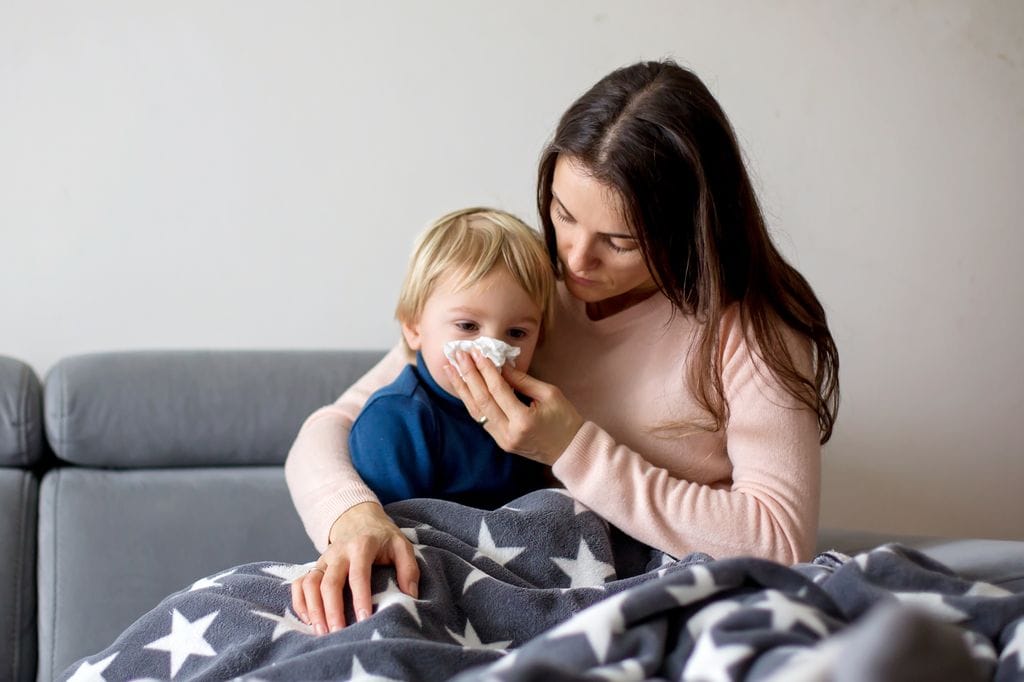 Madre cuida a su hijo, costipado