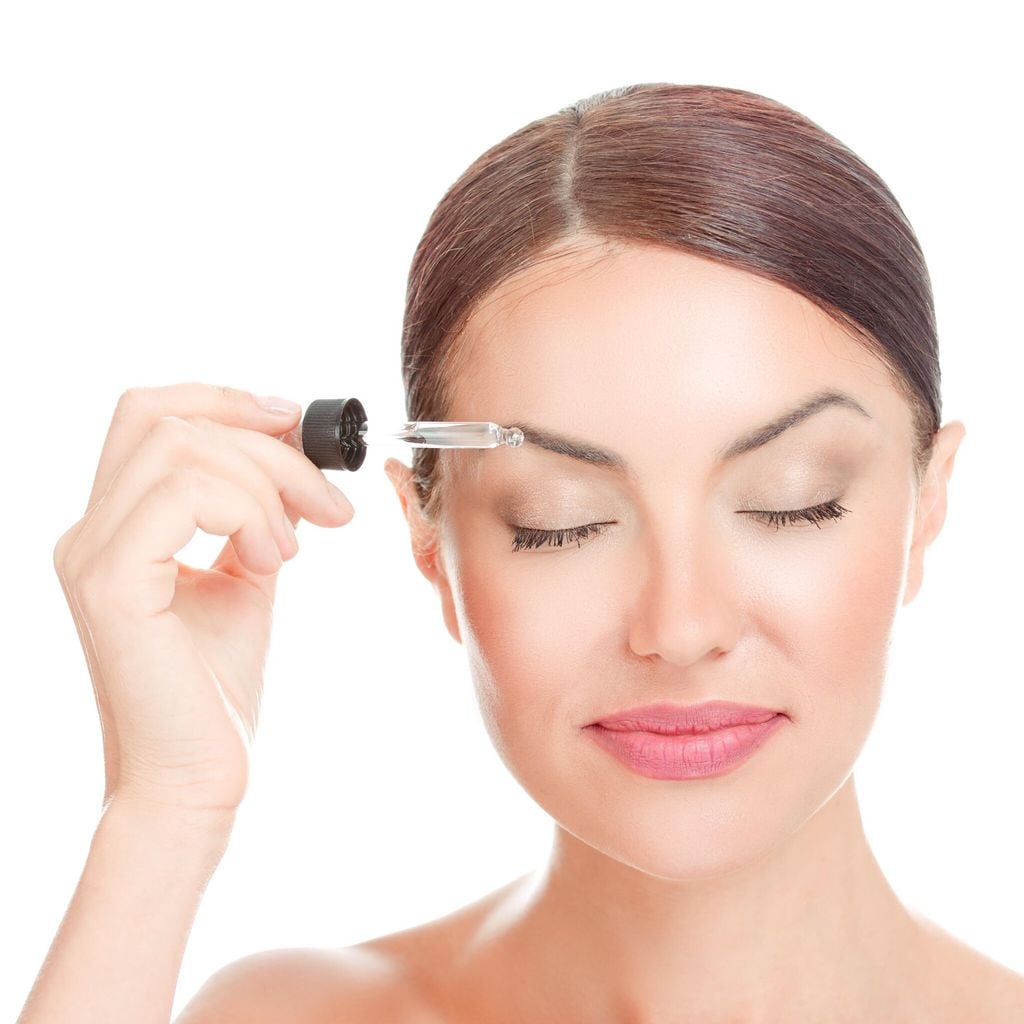 mujer aplicando gotas de aceite en cejas