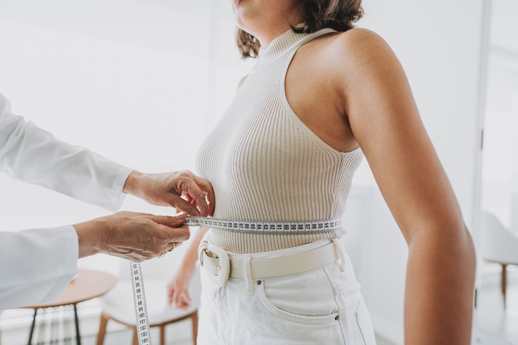 Médico midiendo la cintura a una mujer