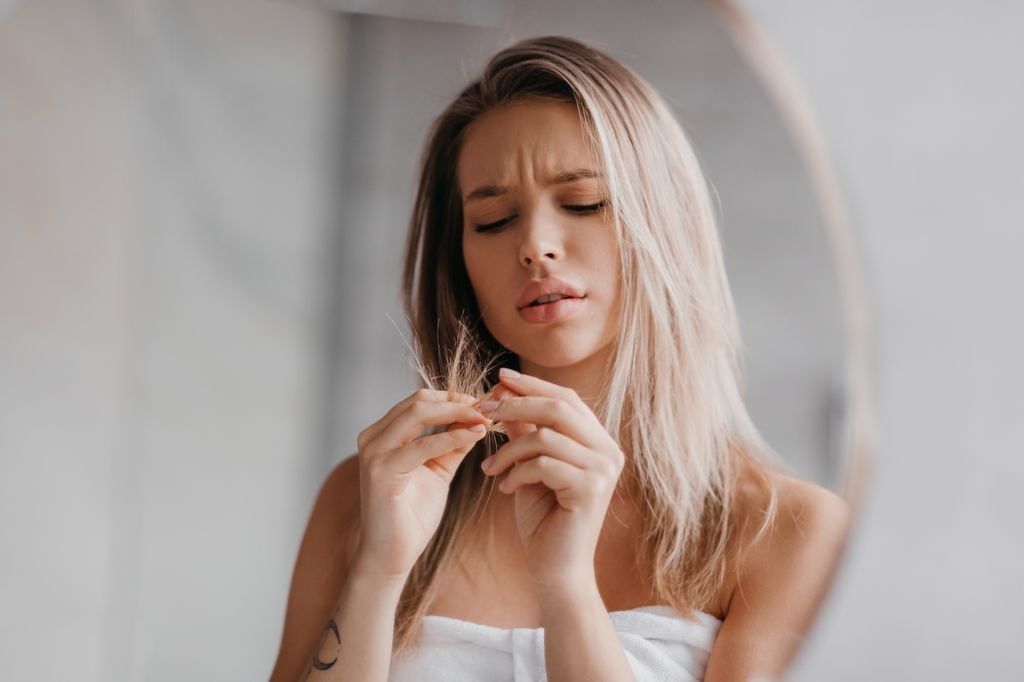 mujer preocupada mirando las puntas de su cabello