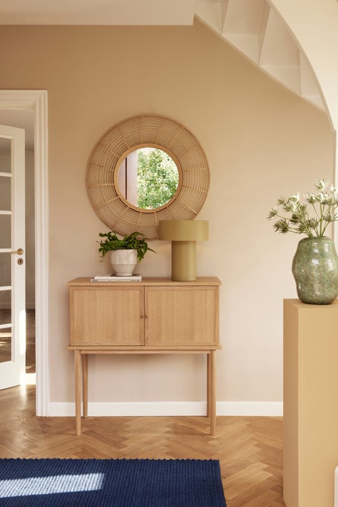 Hallway with wooden sideboard and round mirror on the wall