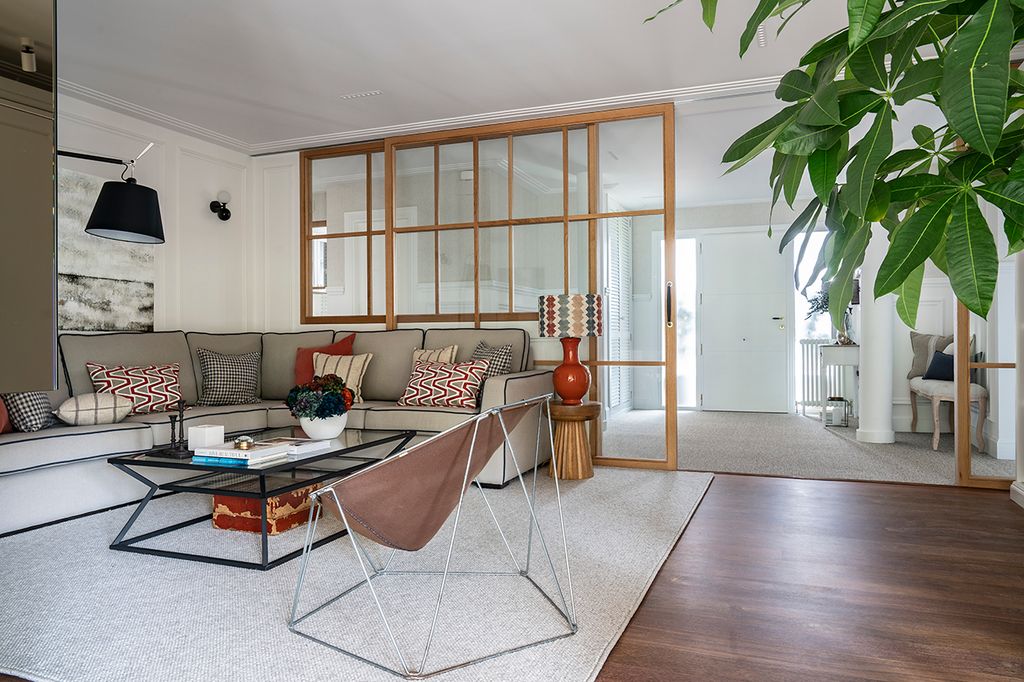 Salón separado del recibidor por un tabique de cristal con cuarterones de madera