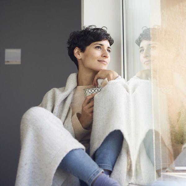 Mujer con manta mirando por la ventana