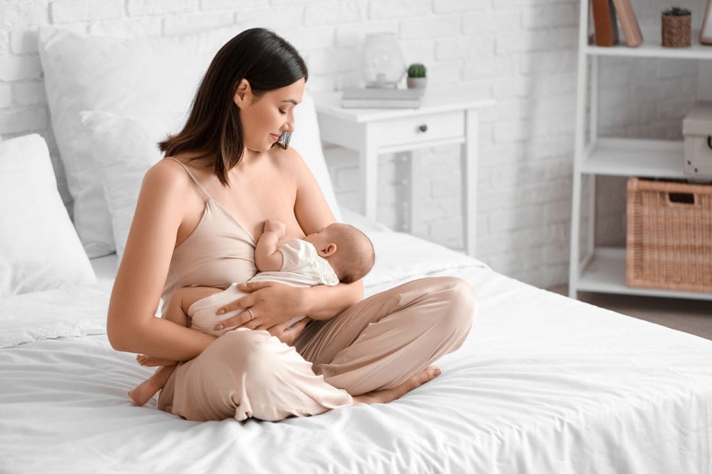 Mujer dando el pecho a su bebé en la cama