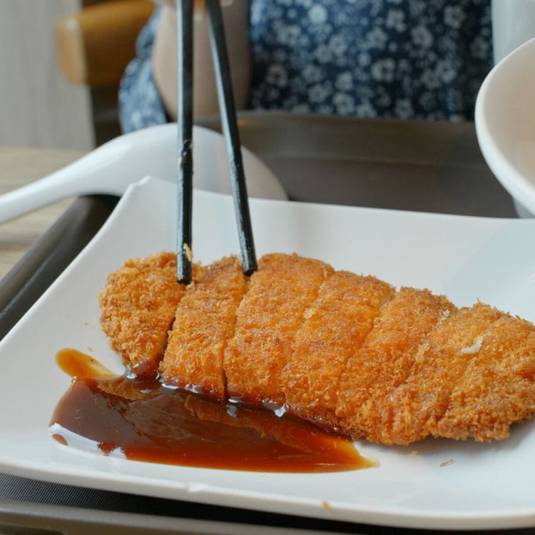 'Tonkatsu' troceado con salsa y palillos