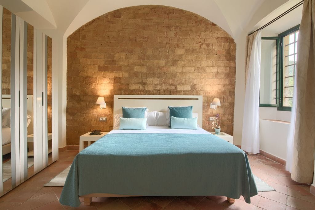 Dormitorio con pared de piedra y ropa de cama azul
