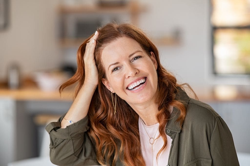 mujer madura sonriendo mientras se toca el pelo