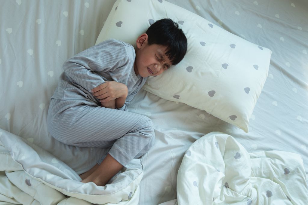 Niño con dolor de tripa acostado en la cama