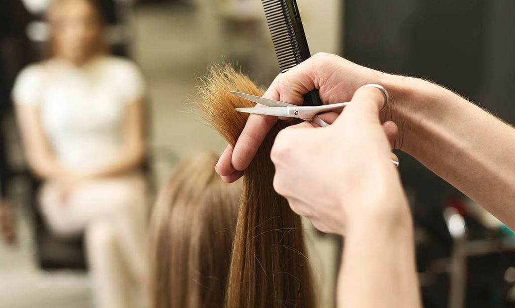 mujer recibiendo un corte de puntas del cabello en una peluquer a