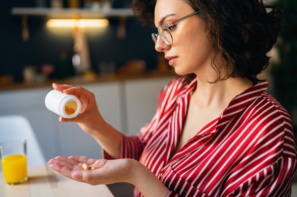 mujer con un bote de suplementos vitamínicos