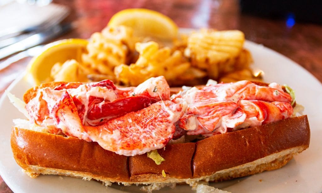 Maine lobster roll on a plate with waffle fries