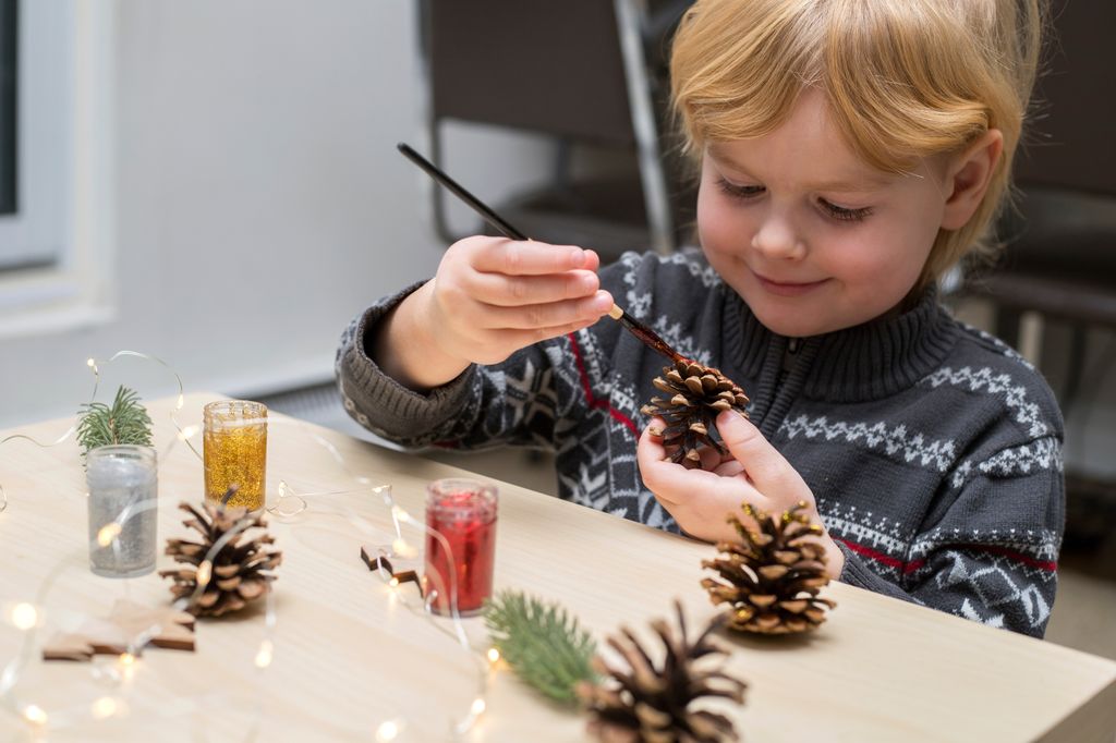 Niño pequeño pintando piñas en Navidad