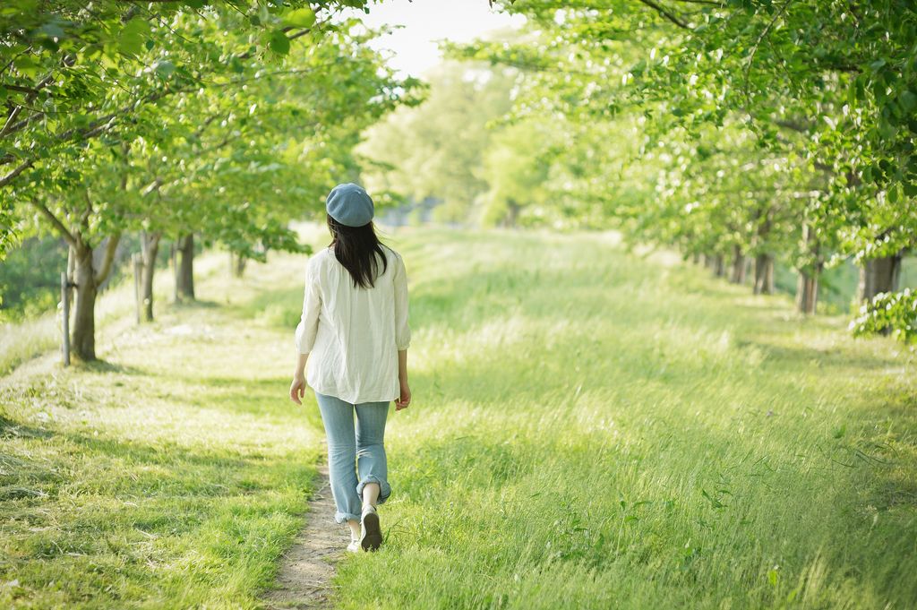 Mujer caminando rodeada de árboles verdes 