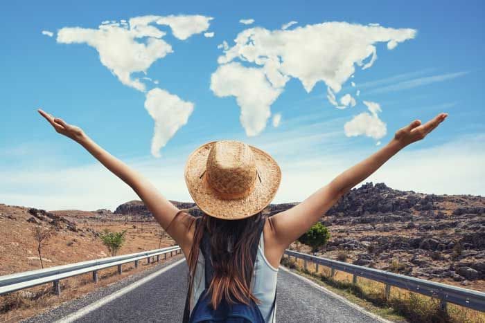 mujer feliz viajando con un mapa del mundo de nubes