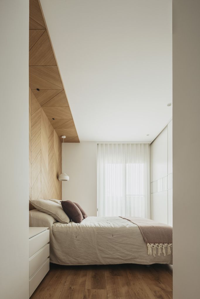 Dormitorio de estilo minimalista cálido con pared del cabecero revestida de madera