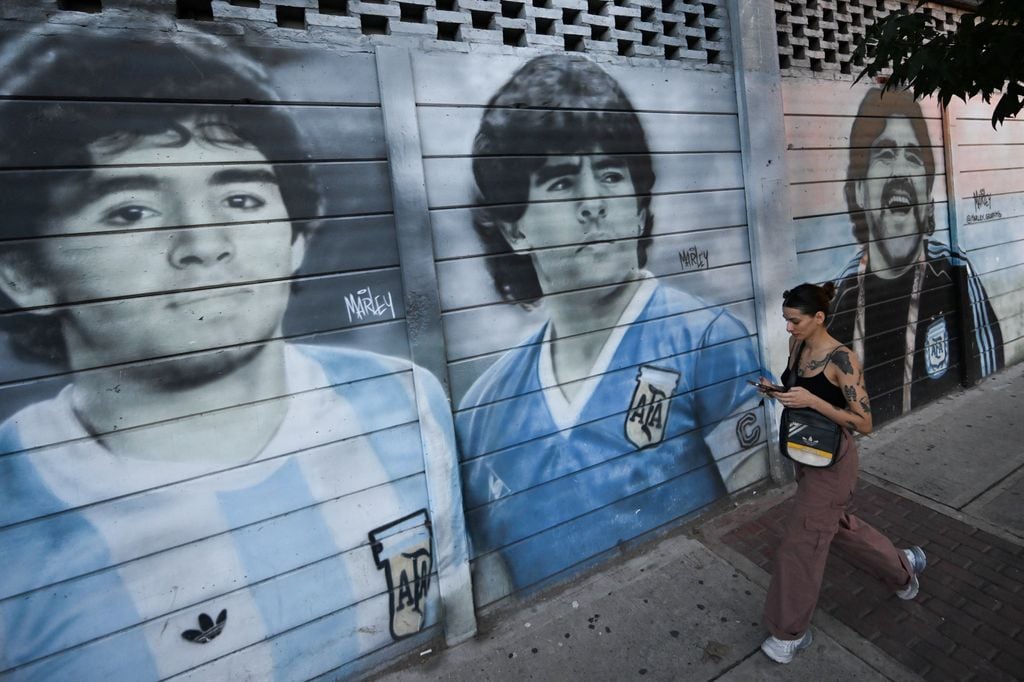 Una mujer camina junto a murales de Diego Maradona en el estadio que lleva su nombre, hogar de Argentinos Juniors, en el barrio de La Paternal, Buenos Aires