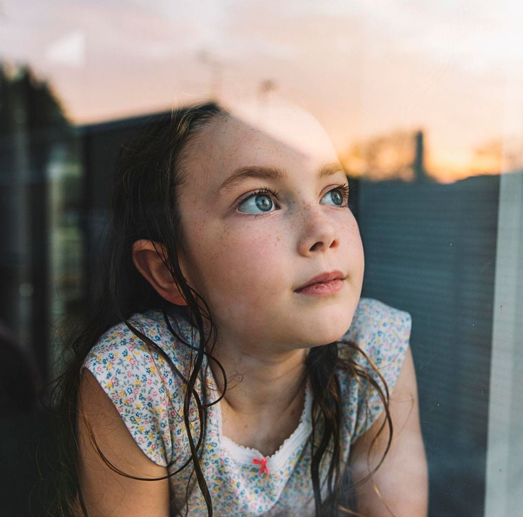 Niña mira por la ventana