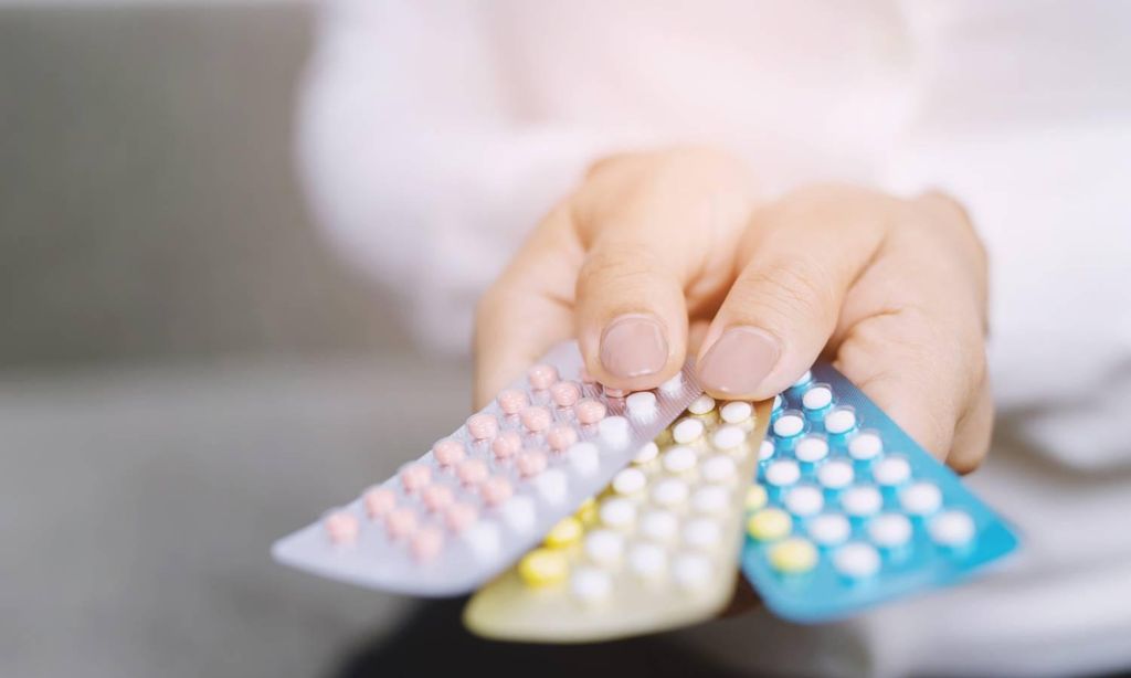 mujer con pastillas anticonceptivas en la mano