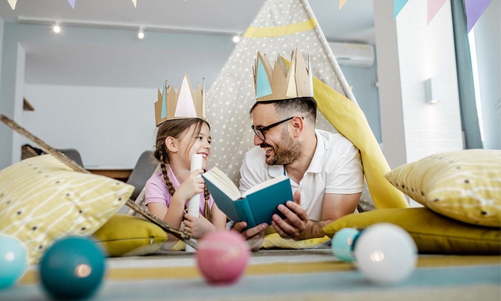 father is reading a book to the daughter