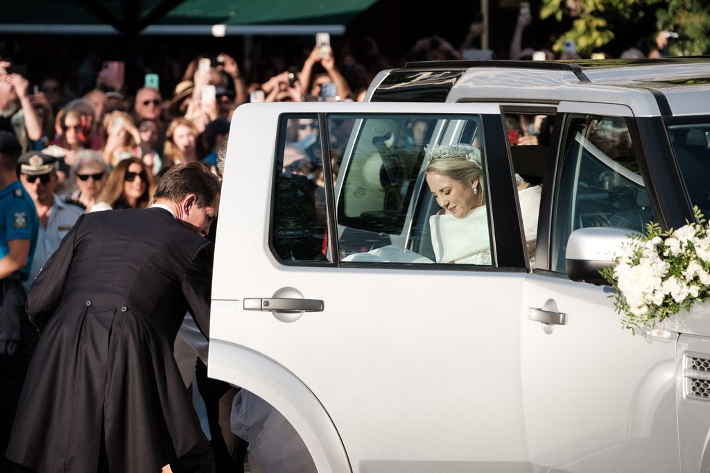 Teodora de Grecia sale del coche nupcial mientras recibe la ayuda de su hermano, el príncipe Pablo