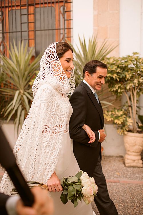 La boda de Cristina con un vestido satinado y capa
