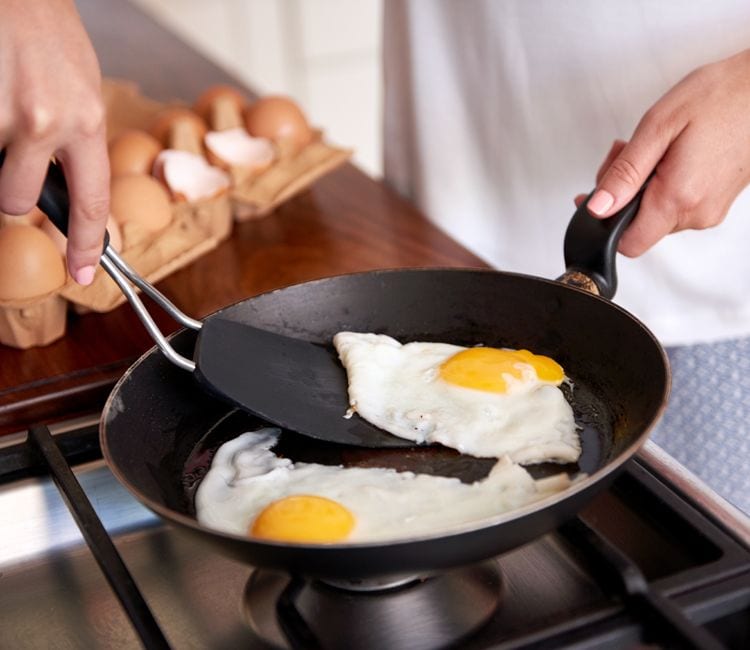 Sacando huevos de una sartén con una espumadera de silicona