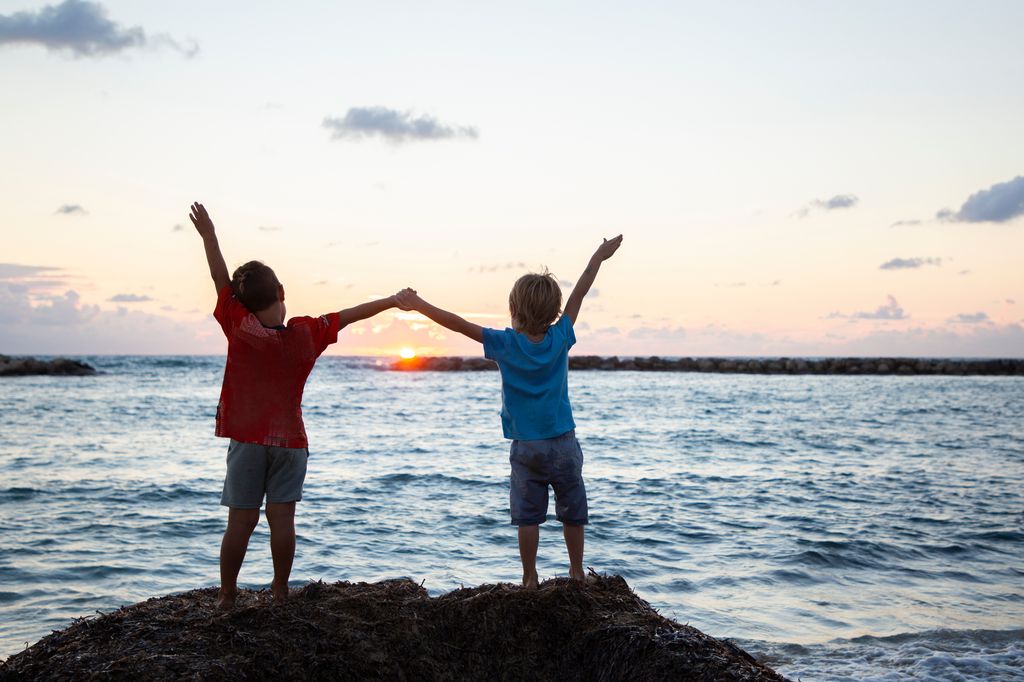 Niños con las manos cogidas delante del mar, en contexto de frases de paz para niños