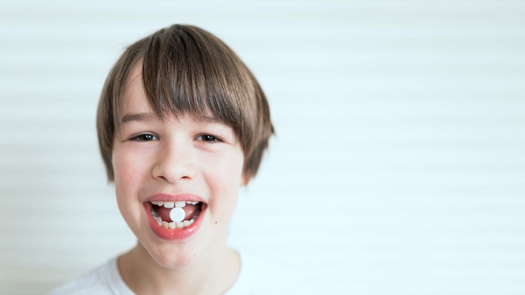 Niño con pastilla en la boca