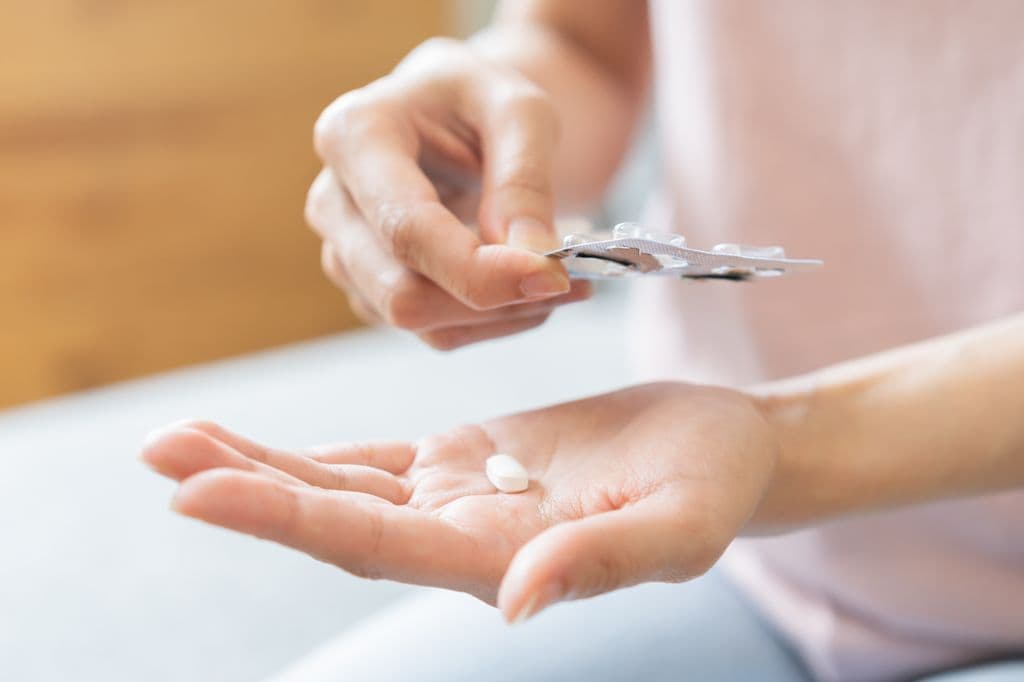 manos de mujer con pastillas para el dolor