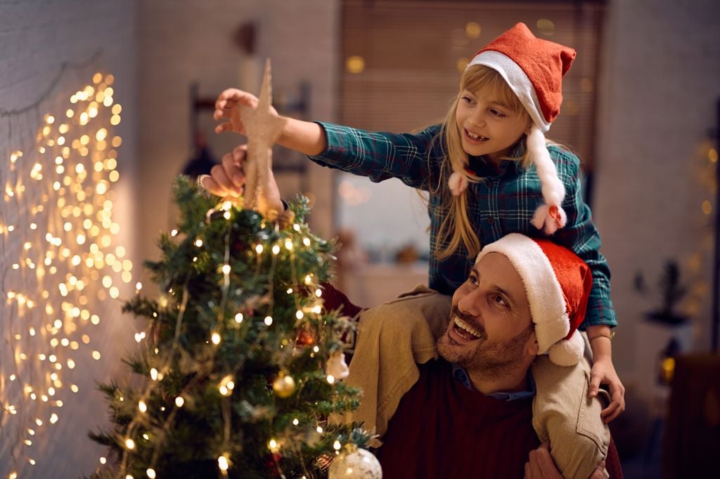 Padre e hija poniendo la estrella del árbol de Navidad