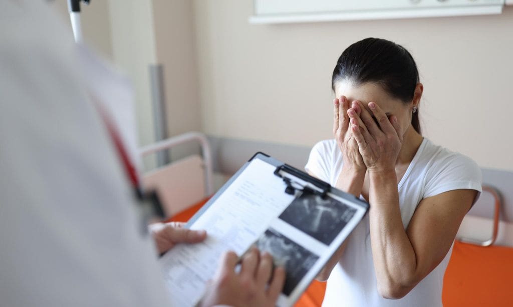 Doctor holding documents in front of crying patient in clinic