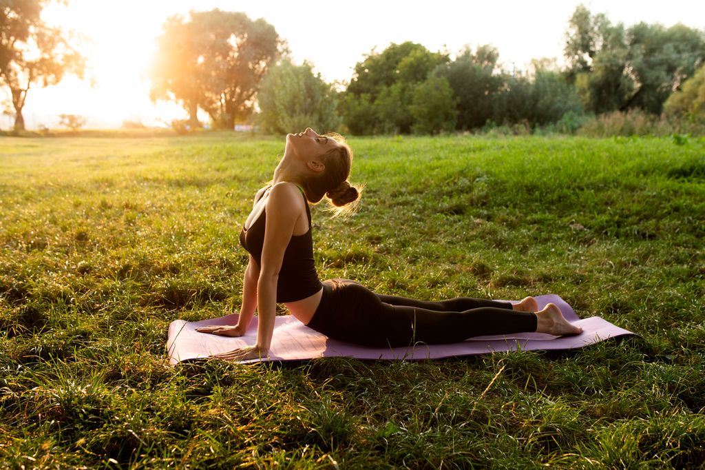 mujer joven practicando yoga al aire libre al atardecer