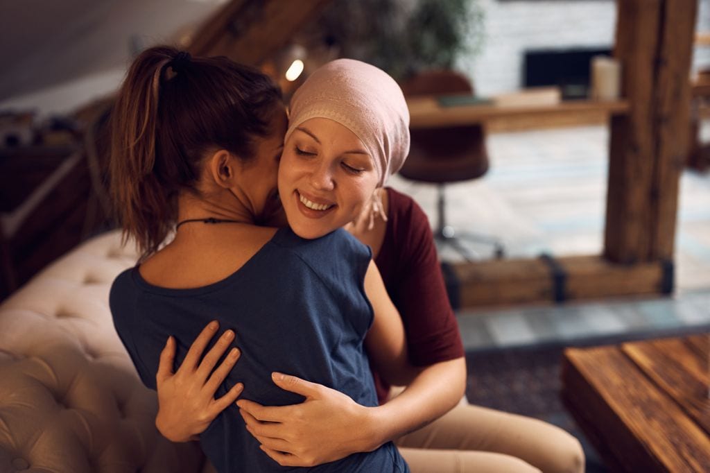 Mujer con cáncer abrazada a una amiga que ha ido a visitarla
