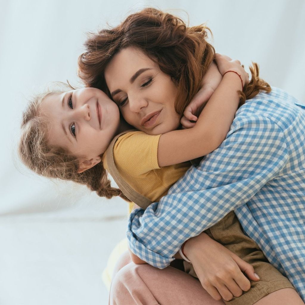 madre abrazando a su hija en el sof 