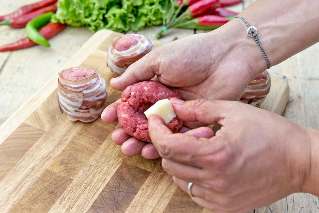 Manos rellenando albóndigas de carne picada con queso