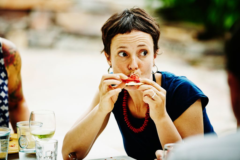 Mujer comiendo un trozo de pizza